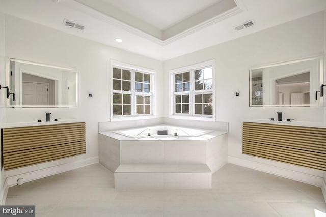 bathroom featuring tile patterned floors, a relaxing tiled tub, vanity, and a tray ceiling