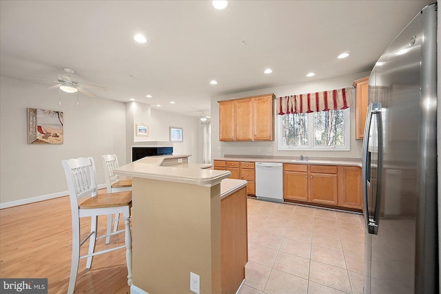 kitchen featuring a kitchen bar, stainless steel fridge, white dishwasher, light hardwood / wood-style floors, and a kitchen island