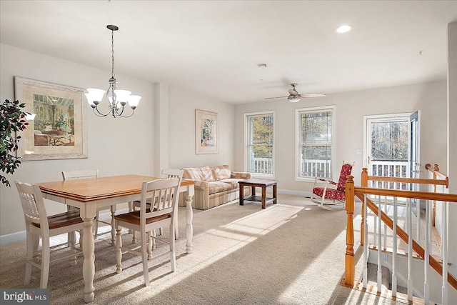 carpeted dining room featuring ceiling fan with notable chandelier