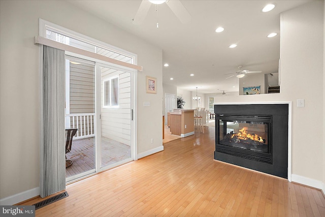 living room featuring a multi sided fireplace and light hardwood / wood-style floors