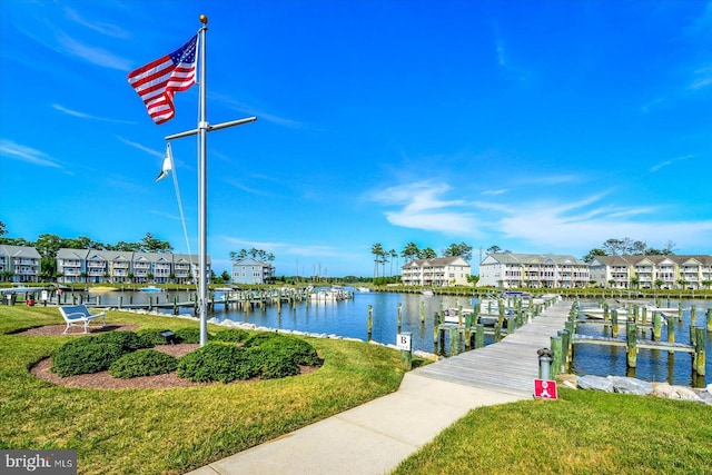 view of dock featuring a lawn and a water view