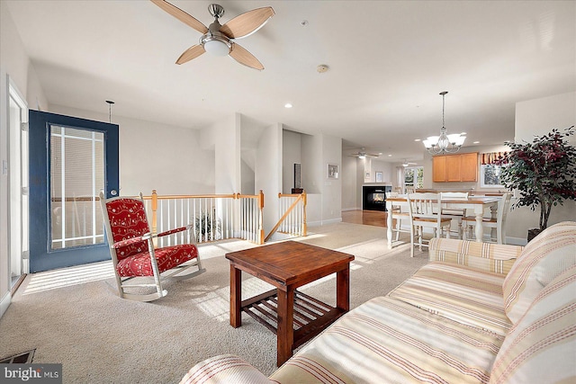 living room featuring light colored carpet and ceiling fan with notable chandelier