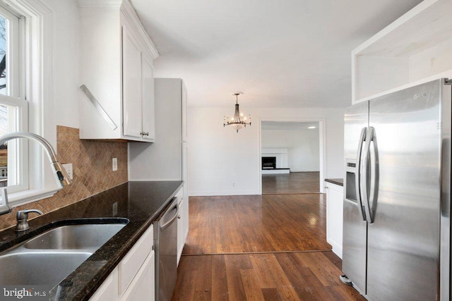 kitchen featuring sink, dark wood-type flooring, dark stone counters, white cabinets, and appliances with stainless steel finishes