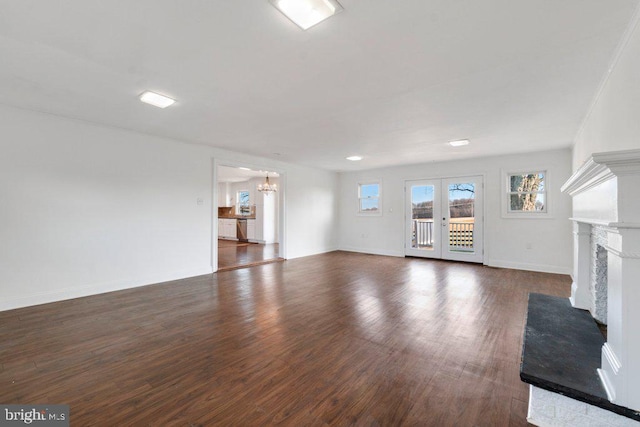 unfurnished living room with french doors, dark hardwood / wood-style floors, and an inviting chandelier