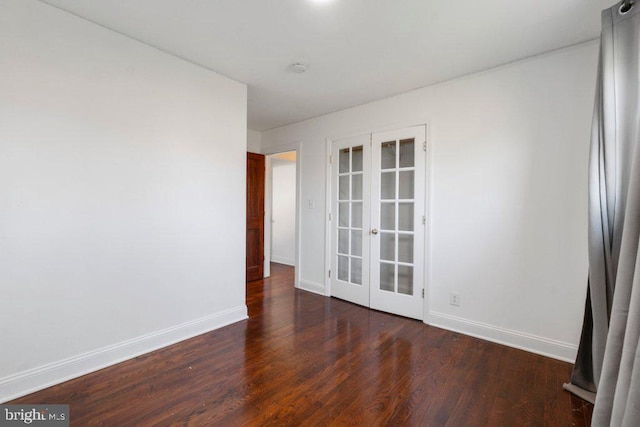 empty room featuring french doors and dark wood-type flooring