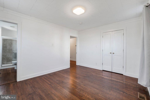 unfurnished bedroom with ornamental molding and dark wood-type flooring