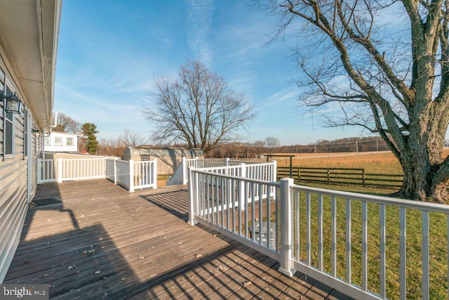 wooden deck featuring a rural view, a storage shed, and a yard