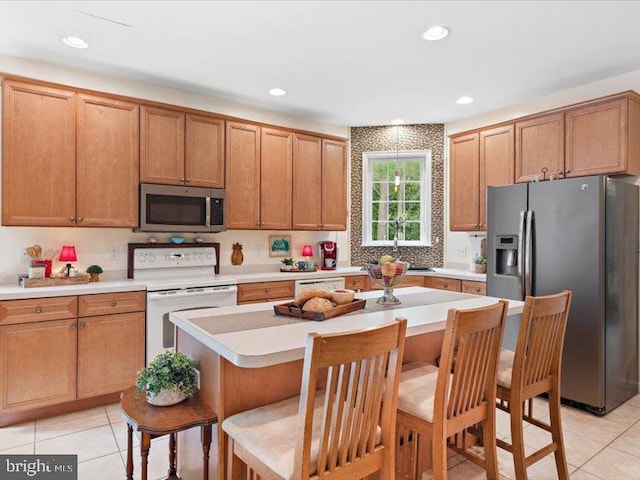 kitchen with a breakfast bar, appliances with stainless steel finishes, a center island, and light tile patterned floors