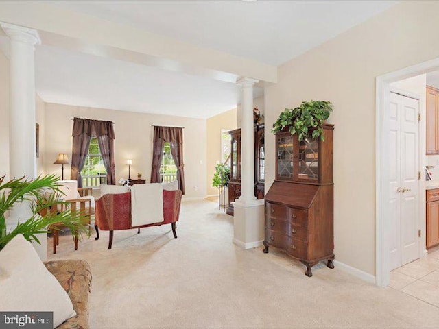 living room featuring beam ceiling, ornate columns, and light carpet