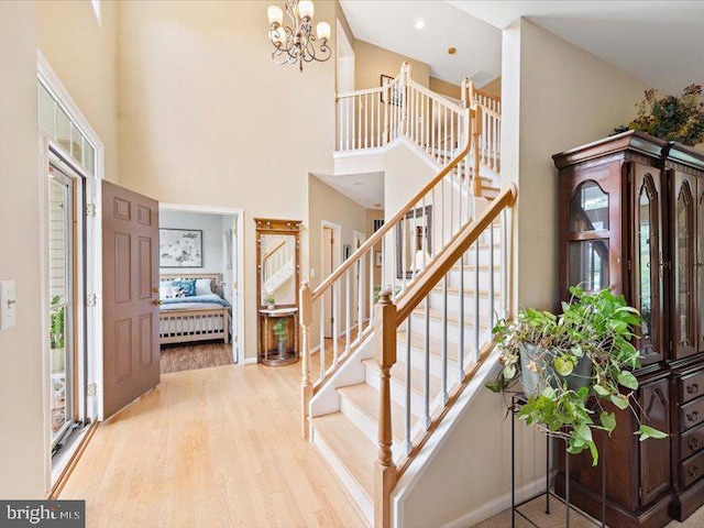 entrance foyer featuring a notable chandelier, light hardwood / wood-style floors, a towering ceiling, and a wealth of natural light