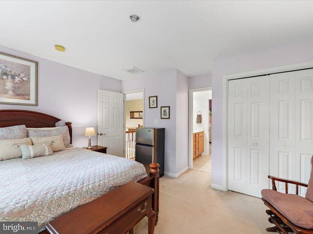 bedroom with stainless steel fridge, connected bathroom, light carpet, and a closet