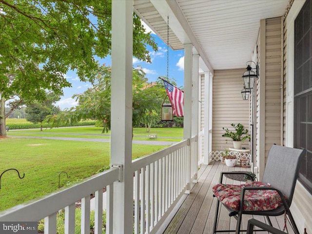 wooden deck with a porch and a lawn