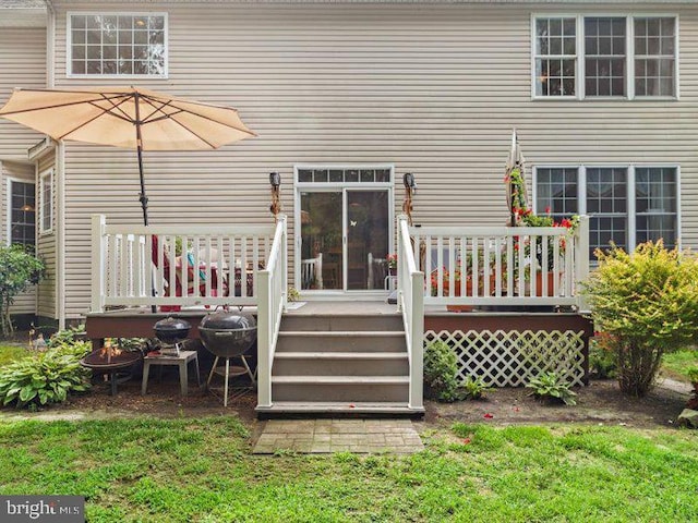 rear view of house featuring a lawn and a deck