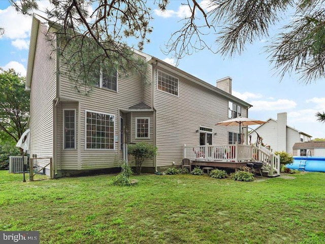 rear view of house with a pool side deck, a yard, and central air condition unit