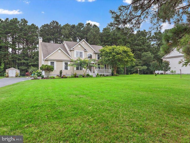 view of front facade featuring an outbuilding, a front lawn, and covered porch