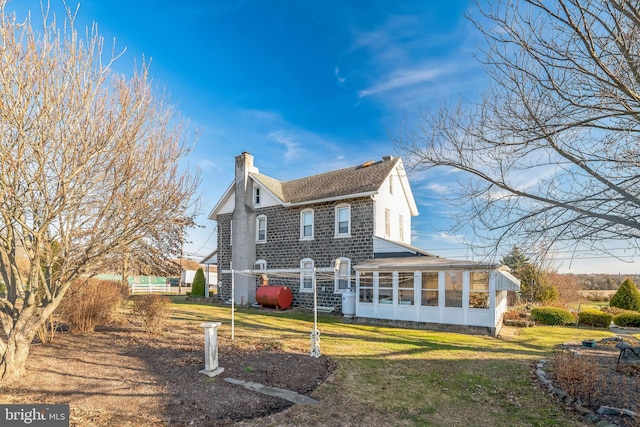 rear view of house with a yard and a sunroom