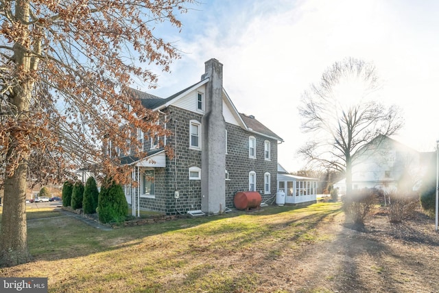 view of side of property featuring a yard and a sunroom