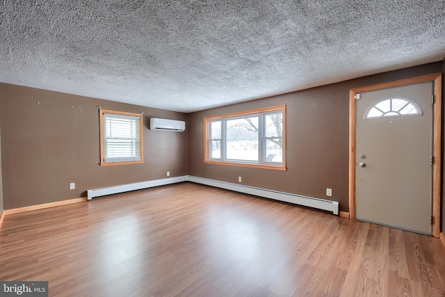 entryway featuring an AC wall unit, a textured ceiling, light hardwood / wood-style floors, and baseboard heating