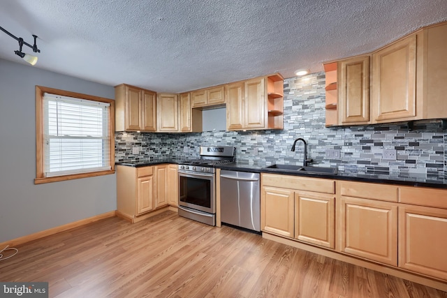 kitchen with light wood-type flooring, stainless steel appliances, sink, tasteful backsplash, and a textured ceiling