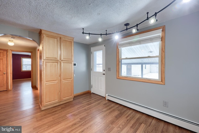 entryway with a baseboard radiator, a textured ceiling, and light hardwood / wood-style flooring