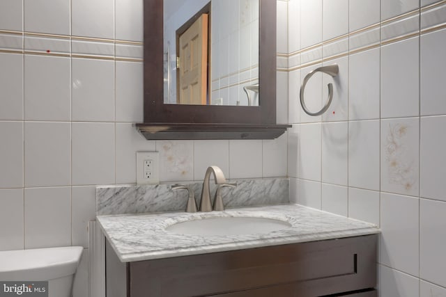 bathroom featuring tile walls, toilet, vanity, and decorative backsplash