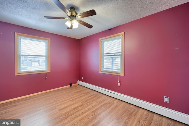 spare room with light wood-type flooring, a textured ceiling, plenty of natural light, and baseboard heating