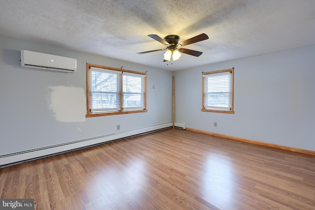 spare room featuring an AC wall unit, a textured ceiling, light hardwood / wood-style floors, and a baseboard radiator