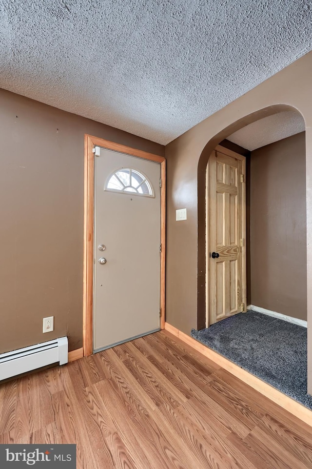 foyer with a baseboard heating unit, a textured ceiling, and light hardwood / wood-style floors