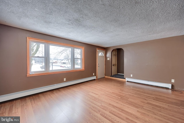 empty room with a baseboard heating unit, a textured ceiling, and light hardwood / wood-style flooring