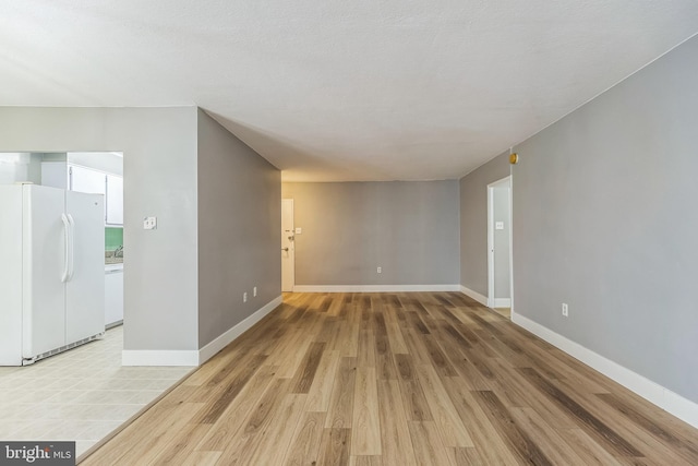 empty room featuring light wood-type flooring and a textured ceiling