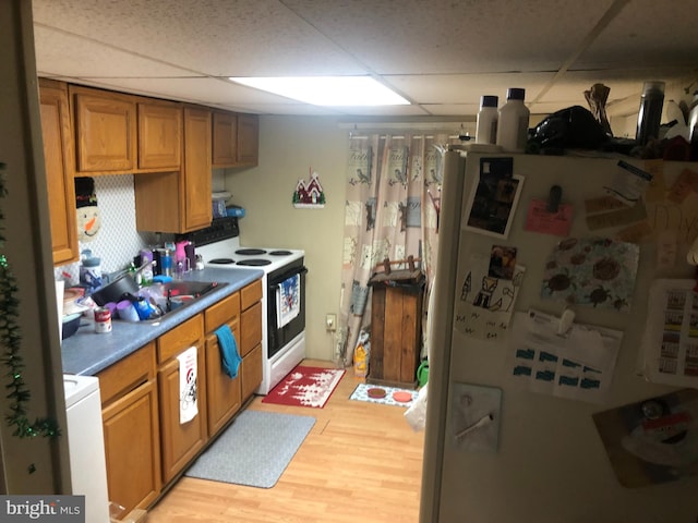 kitchen featuring a drop ceiling, sink, light hardwood / wood-style flooring, white appliances, and washer / dryer