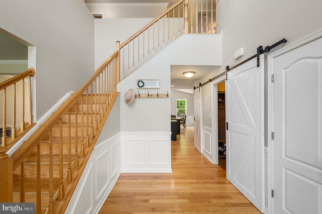 stairway with hardwood / wood-style flooring, a barn door, and ornamental molding