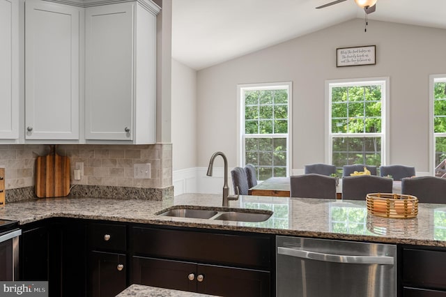 kitchen featuring stainless steel dishwasher, white cabinets, light stone countertops, and vaulted ceiling