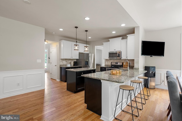 kitchen featuring decorative backsplash, appliances with stainless steel finishes, decorative light fixtures, a kitchen island, and kitchen peninsula