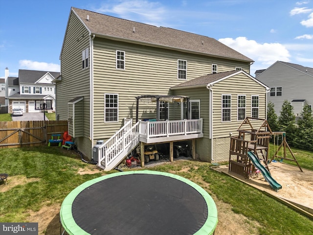 back of house with a playground, a deck, a trampoline, and a yard