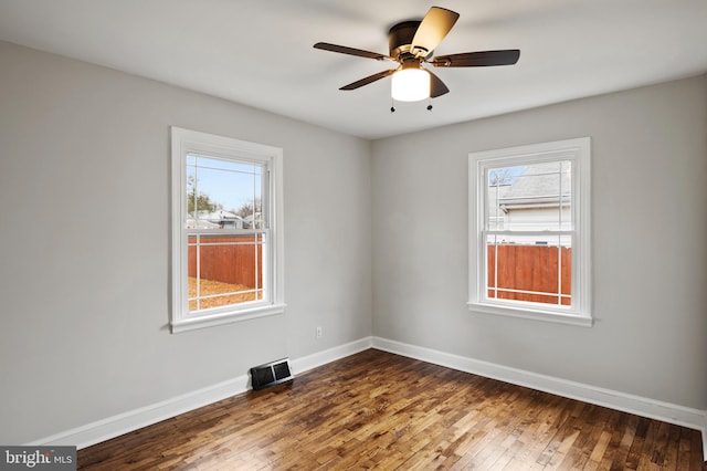 spare room featuring dark hardwood / wood-style floors, ceiling fan, and a healthy amount of sunlight