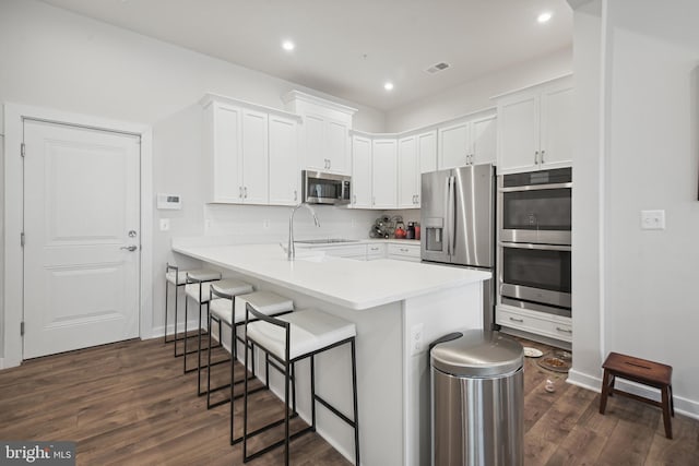 kitchen featuring kitchen peninsula, white cabinetry, a breakfast bar, and stainless steel appliances