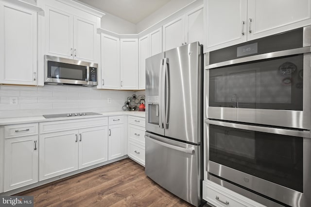 kitchen with appliances with stainless steel finishes, tasteful backsplash, white cabinetry, and dark wood-type flooring