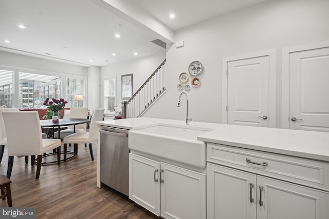 kitchen with dark hardwood / wood-style flooring, white cabinets, stainless steel dishwasher, and sink