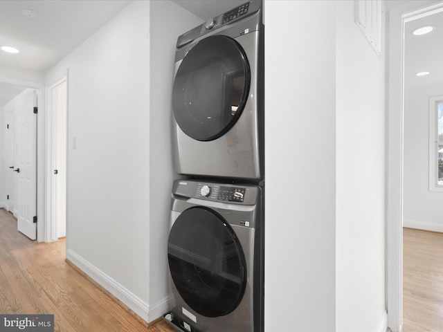 laundry area with light hardwood / wood-style flooring and stacked washer / dryer