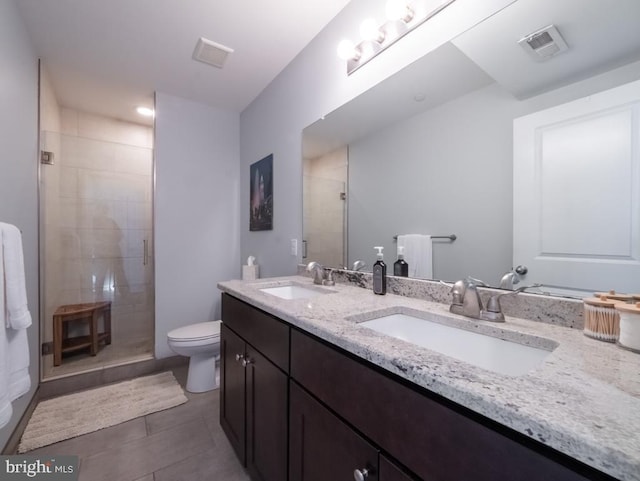 bathroom featuring tile patterned flooring, vanity, a shower with shower door, and toilet