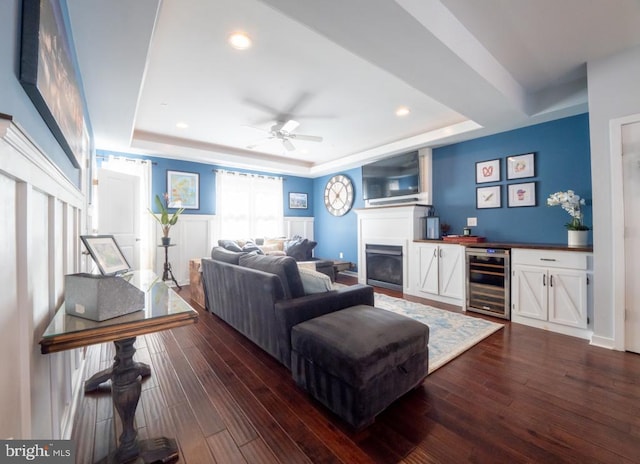 living room featuring a raised ceiling, dark hardwood / wood-style flooring, and beverage cooler