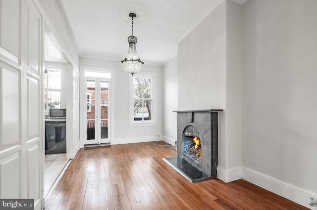 interior space with light wood-style floors, a warm lit fireplace, crown molding, and baseboards