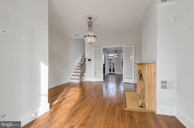 entrance foyer featuring a chandelier, stairway, wood-type flooring, and visible vents