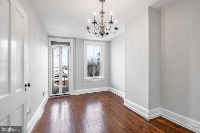 unfurnished dining area with a chandelier, baseboards, and hardwood / wood-style floors