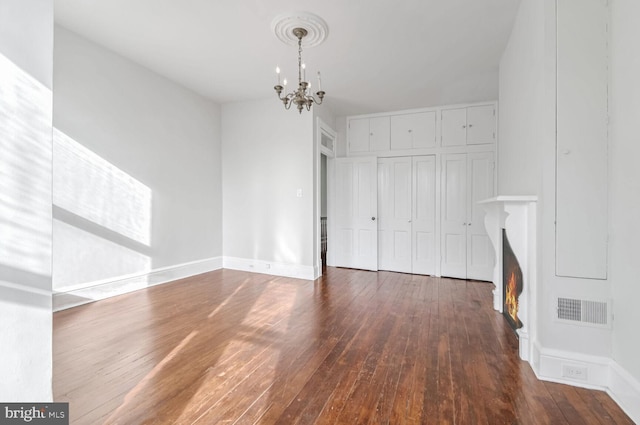 unfurnished bedroom with a closet, visible vents, hardwood / wood-style floors, an inviting chandelier, and baseboards