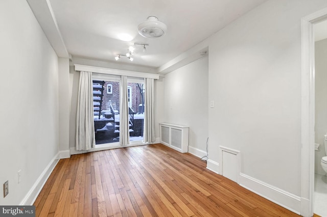 spare room with hardwood / wood-style floors, visible vents, and baseboards