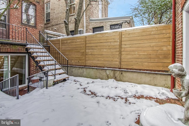 yard covered in snow with fence and stairs