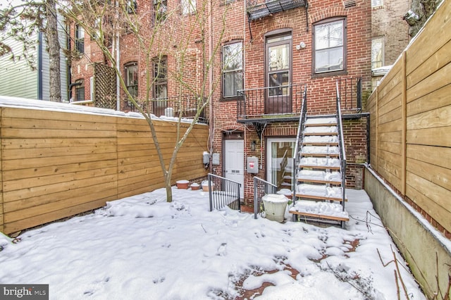 snow covered rear of property with brick siding