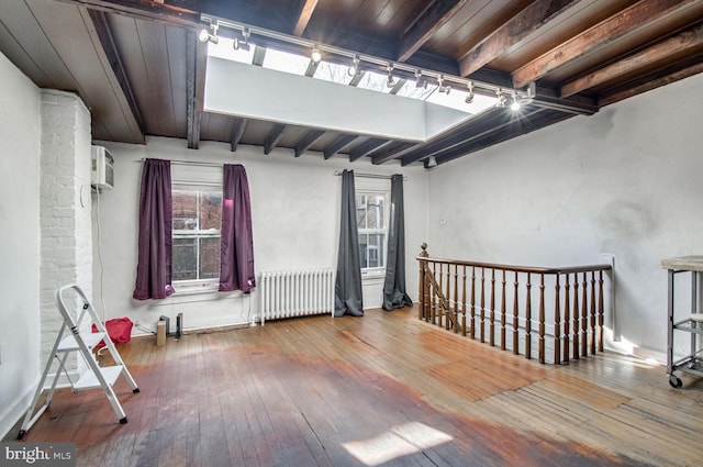 spare room with beam ceiling, radiator, rail lighting, and hardwood / wood-style floors